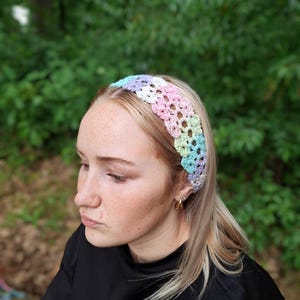 Könnte beinhalten: Ein pastellfarbenes, gehäkeltes Stirnband in Rosa, Blau, Grün und Lila. Das Stirnband wird über der Stirn getragen. Das offene Webdesign sorgt für Atmungsaktivität und ein leichtes Tragegefühl. Dieses Accessoire ist perfekt, um jedem Outfit einen Farbtupfer zu verleihen.