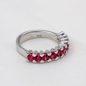May include: A silver band ring with a row of small, bright red gemstones.