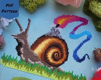 May include: Cross stitch pattern featuring a snail with a candle on its shell, a blue and pink flame, and green grass. The pattern is on a light blue background.