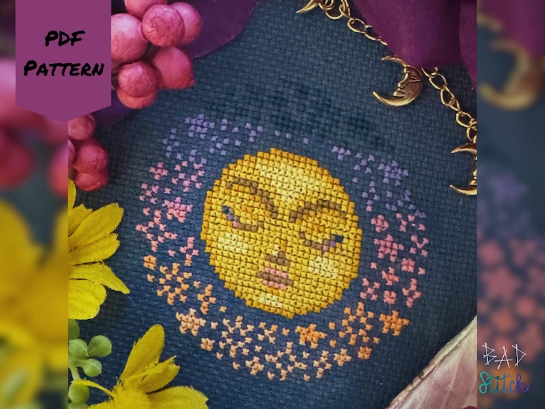 May include: Cross-stitch pattern featuring a yellow moon with closed eyes, surrounded by a ring of pink and purple stars, on a dark blue fabric. The words "PDF PATTERN" are in a purple banner. A gold chain with moon charms is visible.
