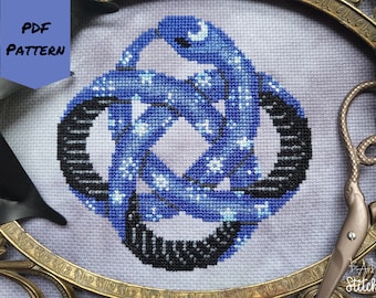 May include: A cross stitch pattern featuring a blue and black knot design with a crescent moon and stars. The pattern is framed in a gold frame.