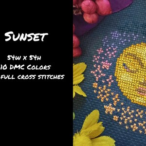 May include: Cross-stitch design featuring a yellow sun with a face, surrounded by pink and orange cross-stitched details, set against a dark blue background. The word "SUNSET" is written in white script. The design is 5x4 inches and uses 10 DMC colors.
