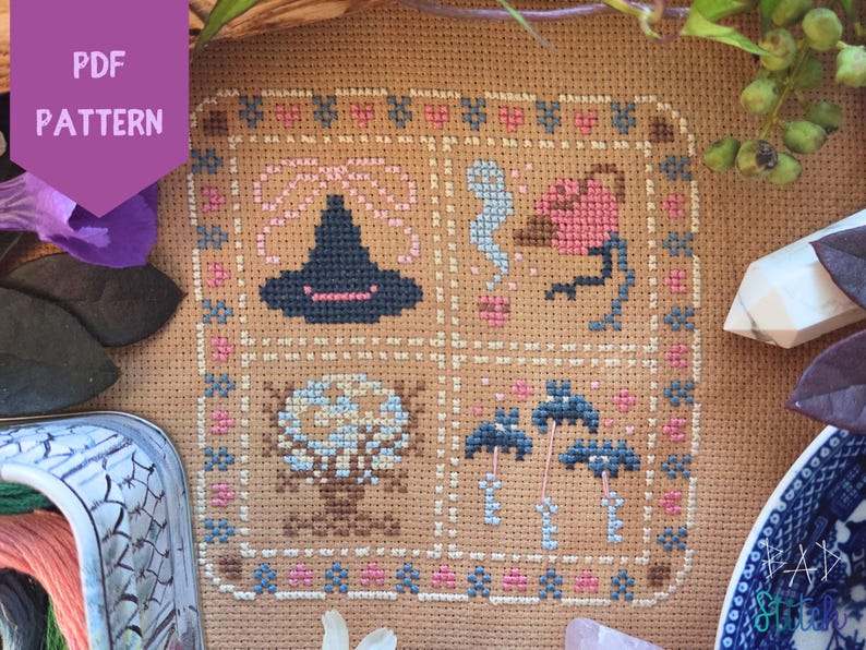 Puede incluir: Un patr&oacute;n de punto de cruz con un sombrero de bruja, un p&aacute;jaro, un &aacute;rbol y setas, todo en un dise&ntilde;o cuadrado. El dise&ntilde;o utiliza hilo azul, rosa y marr&oacute;n sobre un fondo beige. Las palabras "PDF PATTERN" est&aacute;n en una pancarta morada en la esquina superior izquierda.