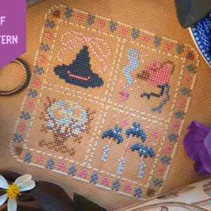 Puede incluir: Patr&oacute;n de punto de cruz con un sombrero de bruja, un fantasma, una flor, una calavera y setas. El dise&ntilde;o est&aacute; enmarcado con detalles en rosa y azul. Las palabras "PDF PATTERN" est&aacute;n en un hex&aacute;gono morado en la esquina superior izquierda.