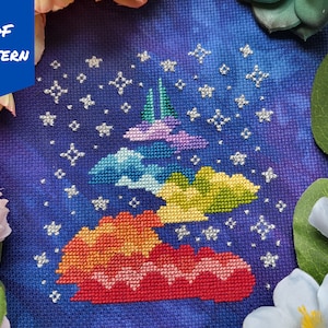 Puede incluir: Un patrón de punto de cruz colorido de una nube arcoíris con estrellas sobre un fondo azul oscuro. El patrón se titula "PDF PATTERN".