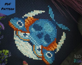 May include: A cross-stitch pattern featuring a stylized blue and orange fish design on a dark blue background. The words "PDF PATTERN" are in the upper left corner. The text "BAD Stitch" is in the lower right corner.