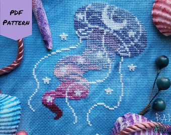 May include: A cross-stitch pattern of a purple and pink jellyfish with white stars on a blue background. The pattern is labeled "PDF PATTERN".
