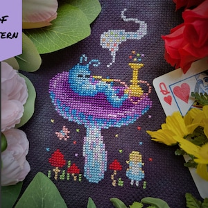 Peut inclure: Modèle de point de croix représentant la chenille d'Alice au pays des merveilles fumant un narguilé sur un champignon. Le motif est sur une toile Aida noire avec du fil coloré. Le motif comprend le texte "BAD Stitch".