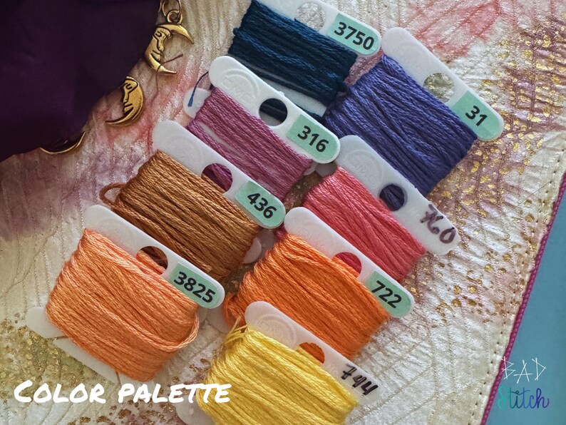 May include: A collection of colorful embroidery floss spools in shades of orange, yellow, pink, purple, and teal. Each spool is labeled with a number. The text "COLOR PALETTE" is visible at the bottom. The image is on a patterned surface.