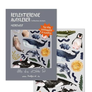 Könnte beinhalten: Eine Bogen mit reflektierenden Aufklebern mit verschiedenen Meeresbewohnern, darunter Wale, Delfine, Orcas, ein Seehund, ein Pinguin, ein Krokodil und ein Seestern. Die Aufkleber sind auf einem grauen Hintergrund mit dem Text "Reflektierende Aufkleber | reflective stickers" und "Meerwelt". Der Text "Für mehr Sichtbarkeit im Dunkeln" ist ebenfalls enthalten, was "Für mehr Sichtbarkeit im Dunkeln" bedeutet.
