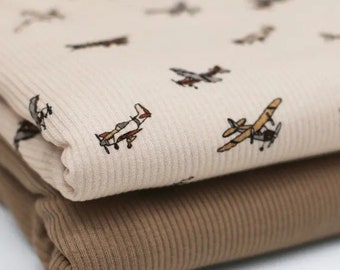 May include: Two pieces of fabric, one beige with a pattern of small airplanes and the other brown, both with a ribbed texture.