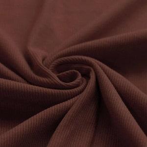 May include: Close-up of a brown ribbed fabric. The fabric has a soft, textured surface.