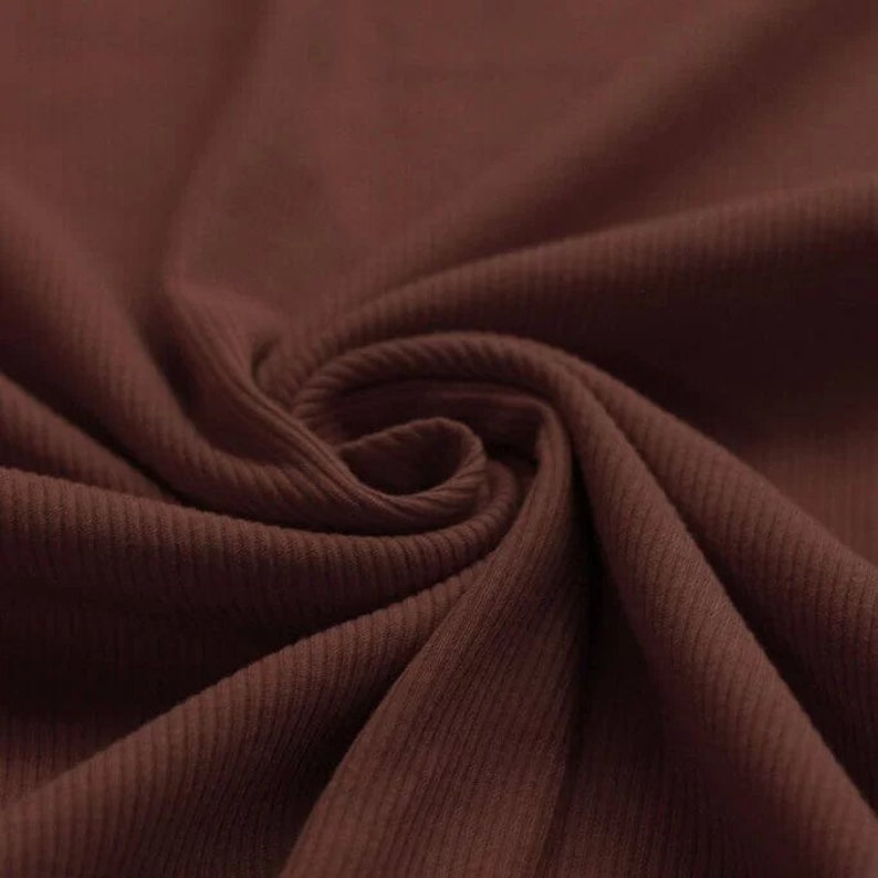 May include: Close-up of a brown ribbed fabric. The fabric has a soft, textured surface.