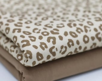 May include: Two pieces of fabric, one with a brown leopard print on a white background and the other a solid brown. The fabric is folded in half.
