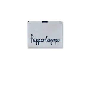 Könnte beinhalten: Weißes gewebtes Etikett mit schwarzem Text, der "Papperlapapp" lautet.