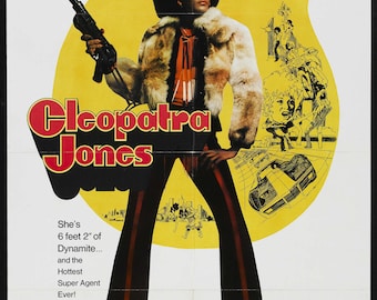 May include: Movie poster for the film "Cleopatra Jones" starring Tamara Dobson. The poster features a woman in a brown fur coat and black pants holding a gun. The text on the poster reads "She's 6 feet 2" of Dynamite... and the Hottest Super Agent Ever!"