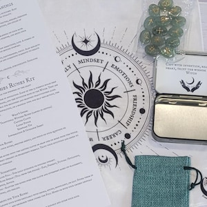 May include: A Witch Runes Kit featuring a teal drawstring bag, a metal tin, and a white cloth with a sun and moon design. The kit includes green rune stones with gold symbols and a printed guide.
