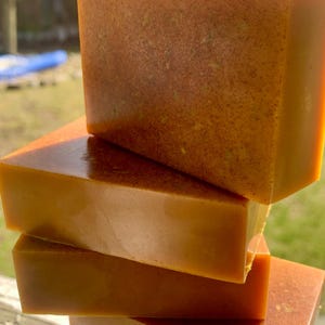 May include: Four bars of handmade soap stacked on top of each other. The soap is a deep orange color and has a slightly textured surface.