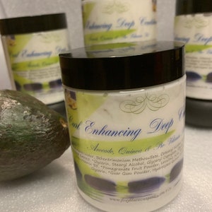 May include: Three white jars with black lids labeled "Curl Enhancing Deep Conditioner Avocado, Quinoa & Ro-Vitamin B5". The jars are sitting on a white surface with a green avocado in the foreground.