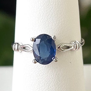 May include: A silver ring with a dark blue oval sapphire gemstone.