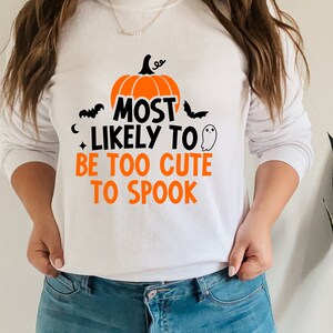 May include: White sweatshirt with a black and orange pumpkin graphic and the text "Most Likely To Be Too Cute To Spook".