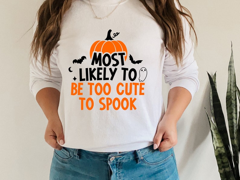 May include: White sweatshirt with a black and orange pumpkin graphic and the text "Most Likely To Be Too Cute To Spook".