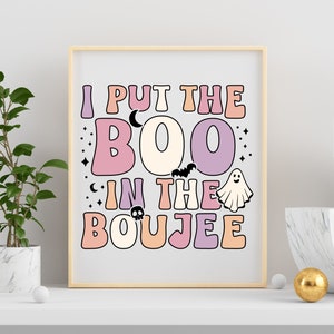 Puede incluir: Un p&oacute;ster imprimible de tem&aacute;tica de Halloween con un esquema de color rosa claro, naranja claro y morado. El p&oacute;ster presenta el texto "I put the BOO in the BOUJEE" con un fantasma, un murci&eacute;lago y una calavera.