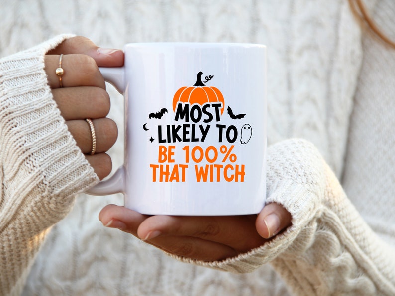 May include: White ceramic mug with a black and orange design. The mug features a pumpkin, bats, and the text "Most Likely to Be 100% That Witch".