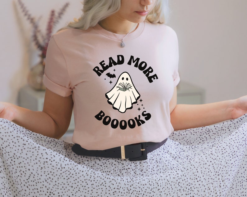 May include: A pink t-shirt with a ghost holding a book and the text "Read More Booooks".