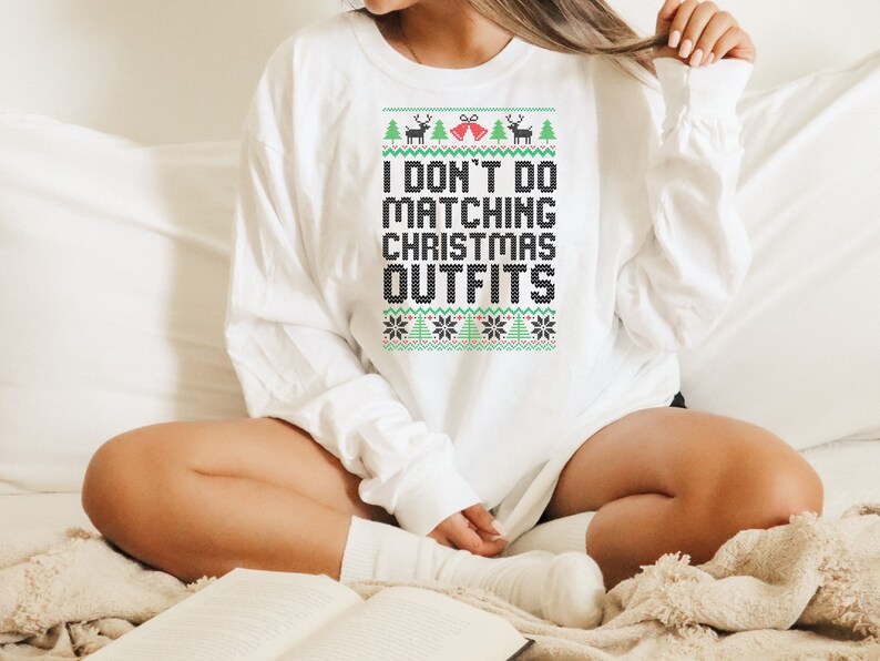 May include: White long-sleeve sweatshirt with a festive Christmas-themed design. The text on the sweatshirt reads "I don't do matching Christmas outfits".