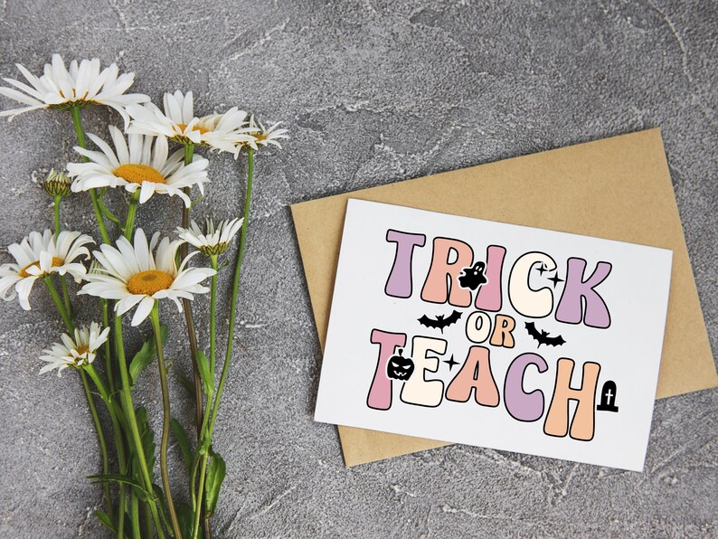 May include: A white card with the text "Trick or Teach" in pink, purple, and orange letters. The text is decorated with a ghost, bats, a pumpkin, and a tombstone. The card is on a brown envelope.