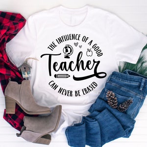 May include: White t-shirt with a black graphic that says "The influence of a good teacher can never be erased". The graphic includes a globe, apple, pencil, and hearts.