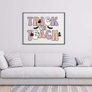 May include: A black framed print with the text "Trick or Teach" in colorful, retro-style letters. The letters are decorated with Halloween icons like bats, ghosts, and pumpkins.