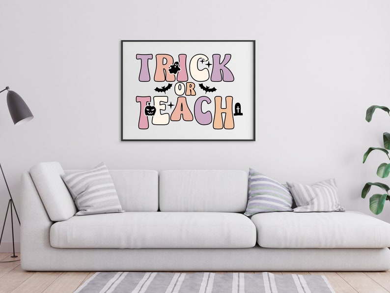 May include: A black framed print with the text "Trick or Teach" in colorful, retro-style letters. The letters are decorated with Halloween icons like bats, ghosts, and pumpkins.