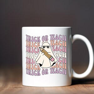 May include: White ceramic coffee mug with a ghost holding a pencil and the text "Trick or Teach" repeated in a rainbow pattern.