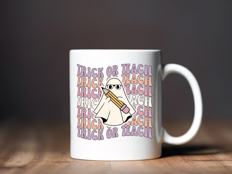 May include: White ceramic coffee mug with a ghost holding a pencil and the text "Trick or Teach" repeated in a rainbow pattern.