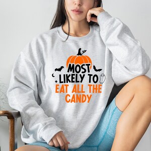 May include: A grey sweatshirt with a pumpkin and the text "Most Likely To Eat All The Candy" printed on the front.