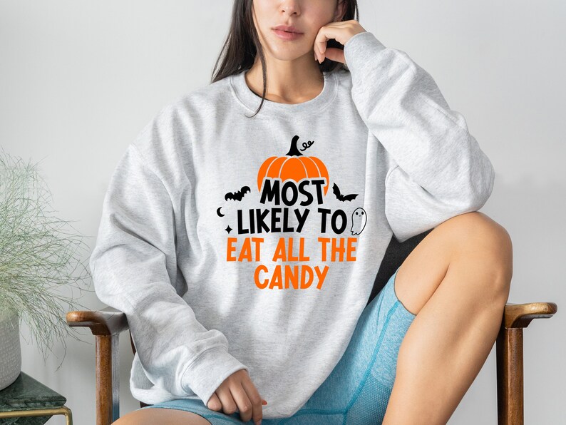 May include: A grey sweatshirt with a pumpkin and the text "Most Likely To Eat All The Candy" printed on the front.