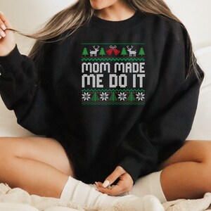 May include: Black Christmas sweater with a green, white, and red design. The sweater has the text "Mom Made Me Do It" in white.
