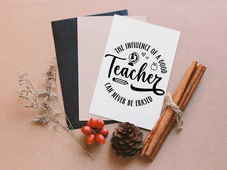 May include: A white card with black text that reads "The influence of a good teacher can never be erased". The text is in a circle with a globe, apple, pencil, and hearts around it. The card is on a brown surface with cinnamon sticks, a pine cone, and red berries.