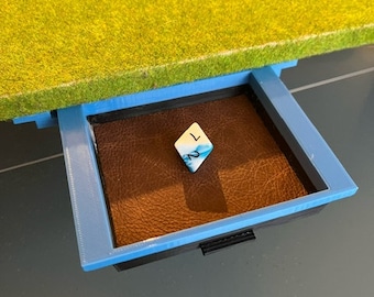 May include: A blue and black drawer with a brown leather bottom. A white and blue dice with the number 1 is in the drawer.
