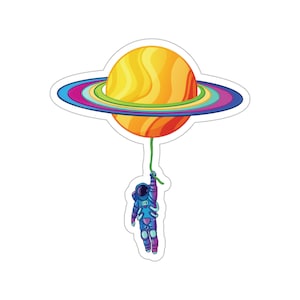 May include: An astronaut in a blue and purple spacesuit holds onto a string attached to a yellow planet with a rainbow ring around it.
