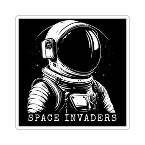 May include: Black and white illustration of an astronaut's head and shoulders against a starry background. The astronaut is wearing a helmet and spacesuit. The text "SPACE INVADERS" is below the astronaut.
