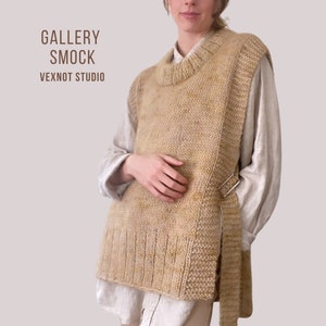 May include: A beige knitted sleeveless sweater with a tie closure. The sweater has a loose fit and a round neckline. The text "GALLERY SMOCK" and "VEXNOT STUDIO" is printed on the image.