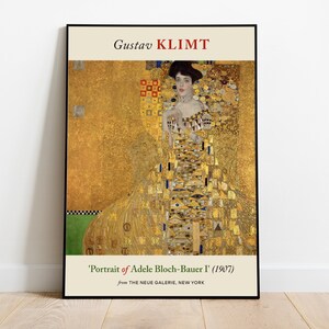 Puede incluir: Un póster con una pintura de Gustav Klimt titulada "Retrato de Adele Bloch-Bauer I" (1907). La pintura representa a una mujer con un vestido dorado sobre un fondo decorativo.