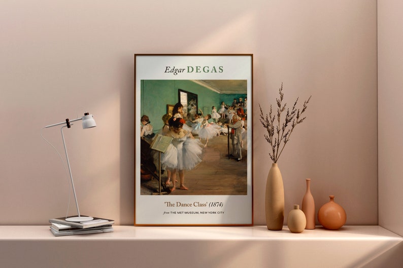 Pu&ograve; includere: Una stampa incorniciata di un dipinto di Edgar Degas intitolato "La Classe di Danza" (1874). Il dipinto raffigura un gruppo di giovani ballerine in uno studio di danza, con una parete verde e un pavimento in legno.