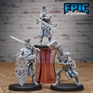 May include: Three unpainted miniature figures of steampunk-style characters. The figures are posed in a fighting stance, each holding a different weapon. The figures are made of a gray plastic material and are ready to be painted.