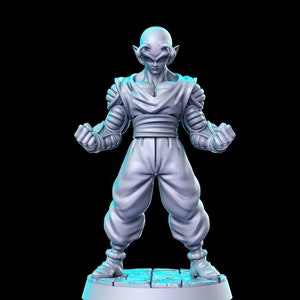 May include: A gray, bald figurine of a character with pointed ears, wearing a white outfit with a dark sash. The figurine is standing on a circular base with a textured surface.