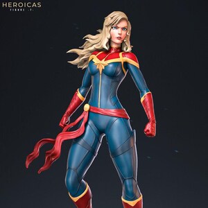 May include: A red, blue, and gold superhero figurine standing on a rocky base. The figurine has long blonde hair and is wearing a red, blue, and gold costume. The figurine is posed in a dynamic stance, with one leg raised and the other bent. The figurine is holding its arms out in front of it, as if it is about to fly.
