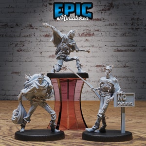 May include: Three gray painted miniature figures of skeletal figures wearing hooded cloaks and holding various props. The figures are standing on black bases. The figure in the center is standing on a clear acrylic pedestal. The figure on the right is holding a sign that says "No Smoking".